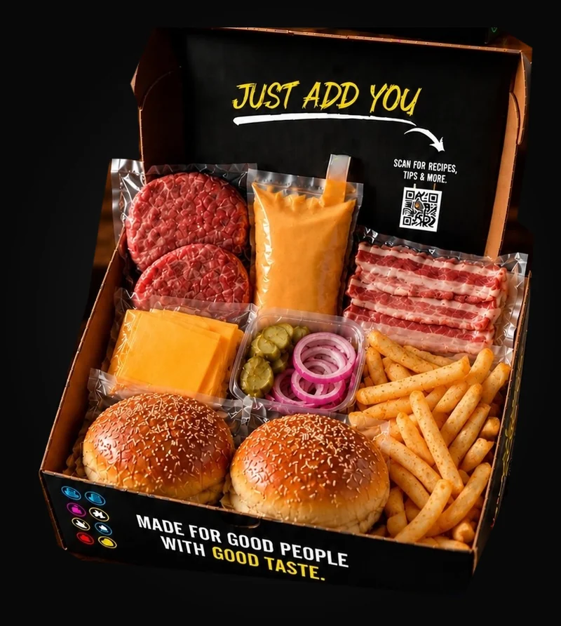 Open burger kit showing patties, sauce, cheddar slices, bacon, pickles, onion, buns and chips